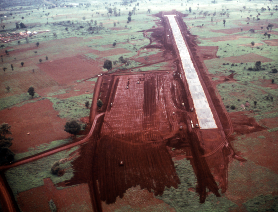 Aerial view of runway in red dirt and green fields